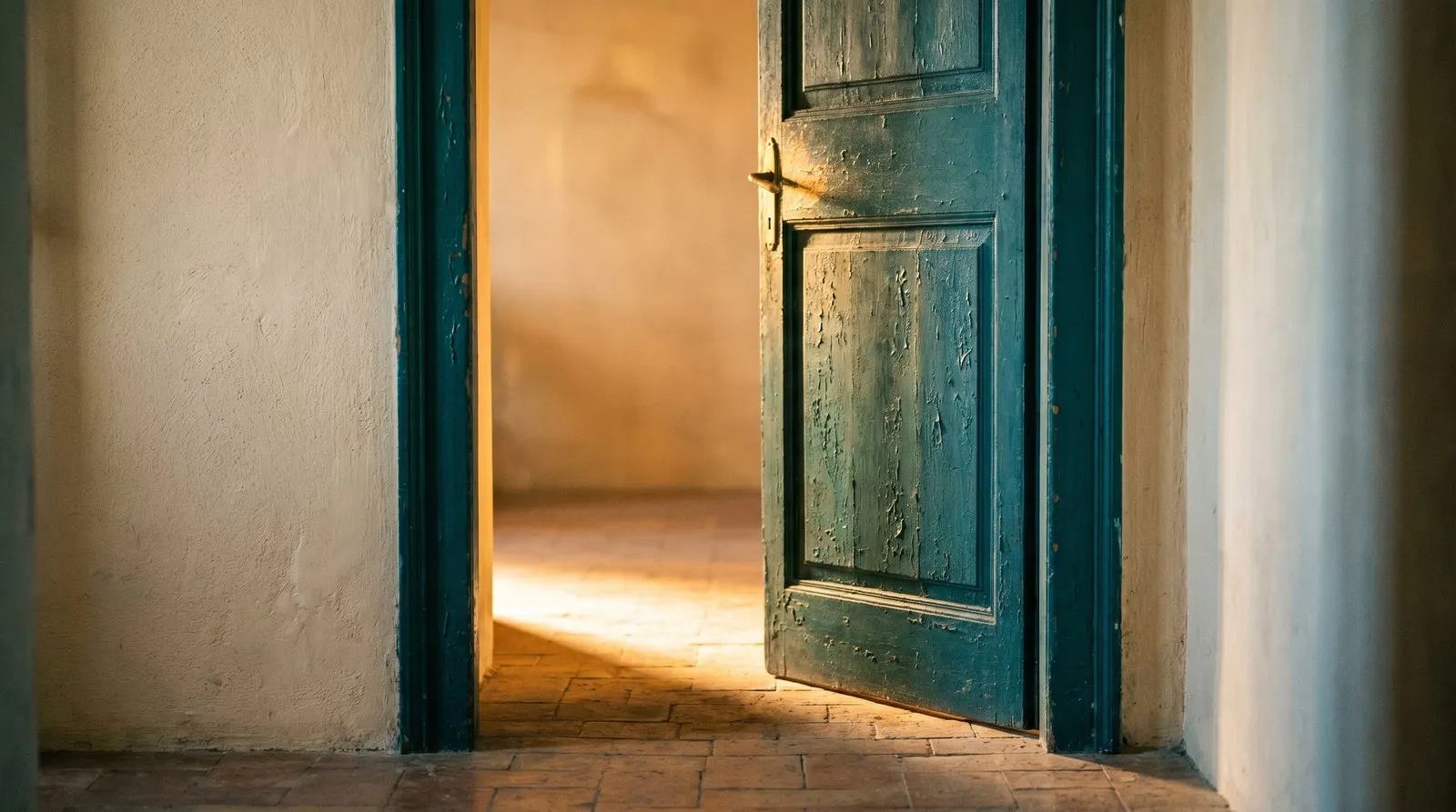 Une porte ancienne peinte en bleu sarcelle, entrouverte, laissant filtrer une lumière dorée chaleureuse.